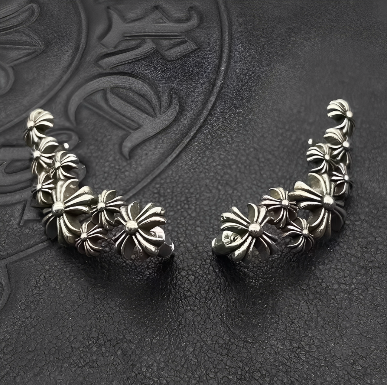 Pair of silver floral earrings on a textured dark background