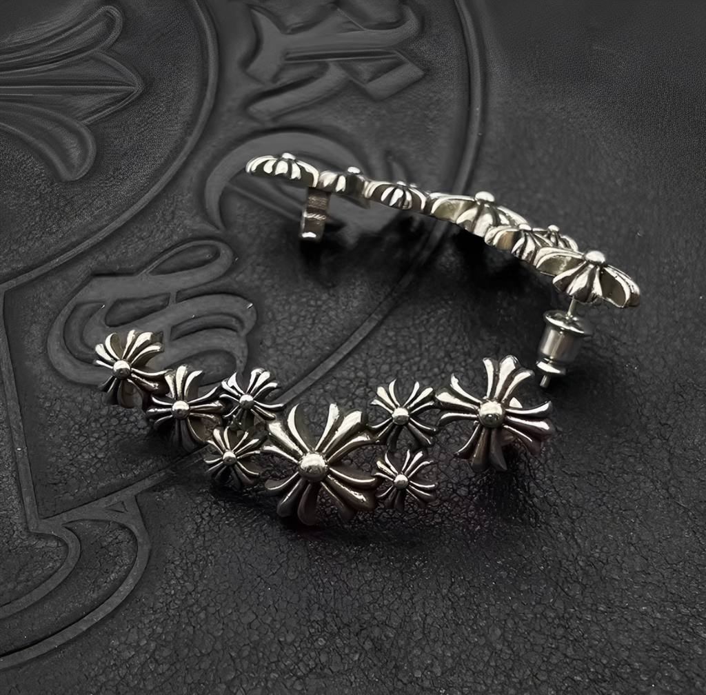 Silver earrings with floral designs on a textured black surface