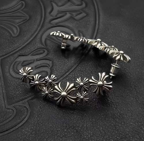 Silver earrings with floral designs on a textured black surface