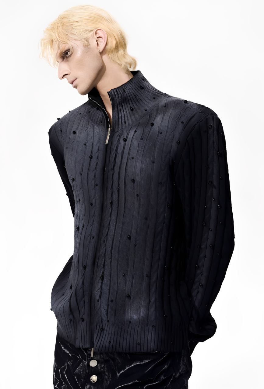 Person wearing a black cable knit sweater with a high collar on a white background