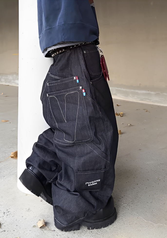 Person wearing black pants with multiple pockets and a visible brand logo, standing against a plain background.